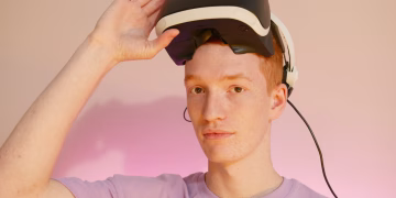 Caucasian man wearing and adjusting a VR headset in a minimalist indoor setting.
