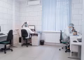 Two laboratory technicians working with computers and microscopes in a clean, modern lab.
