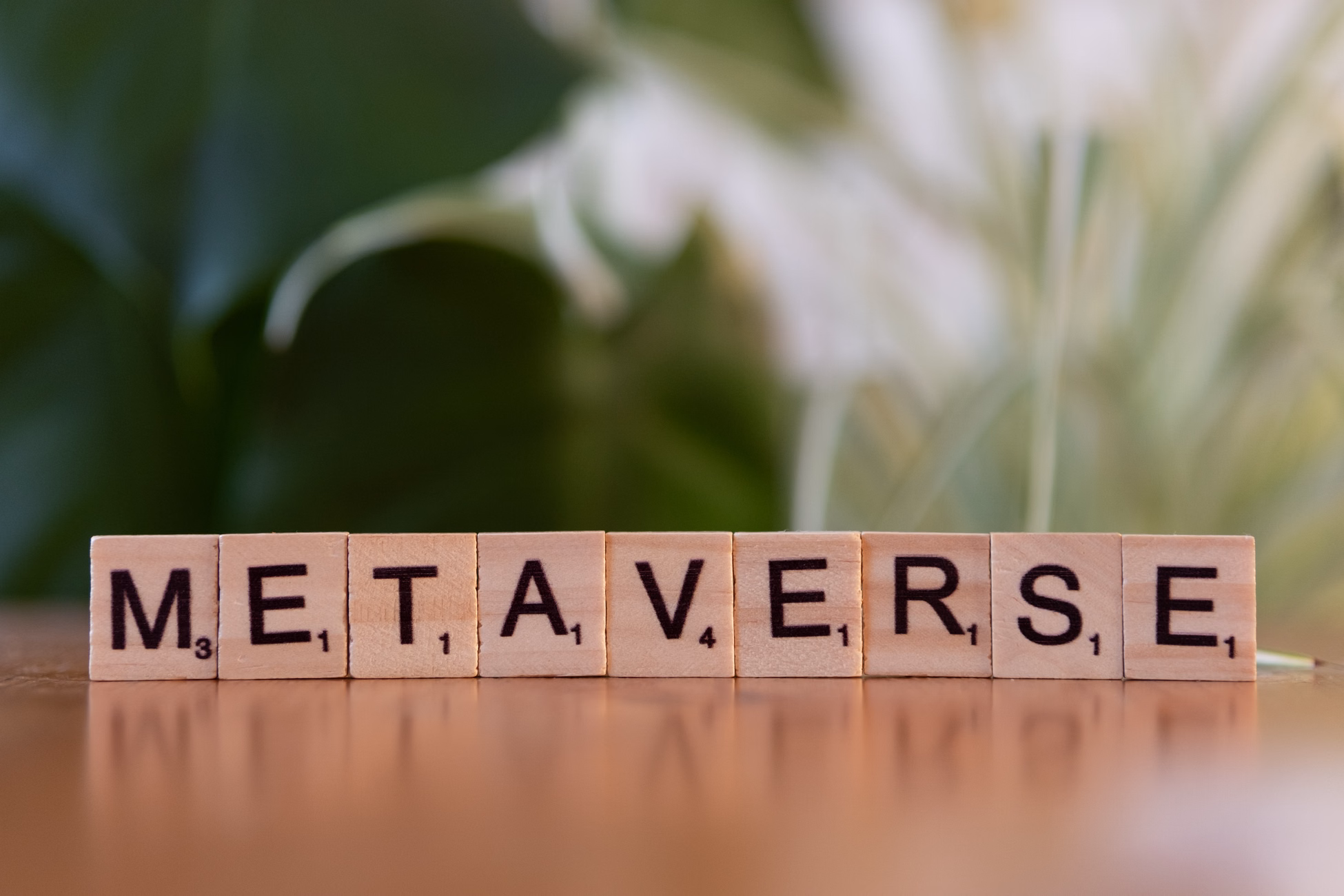 Scrabble letters spelling 'Metaverse' on a wooden surface with a blurred nature background.