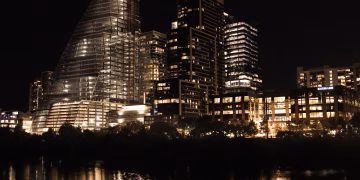 Illuminated skyscrapers reflecting in the river at night in downtown Austin, Texas.