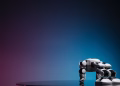 A close-up of a futuristic robot toy on a reflective surface against a gradient background.