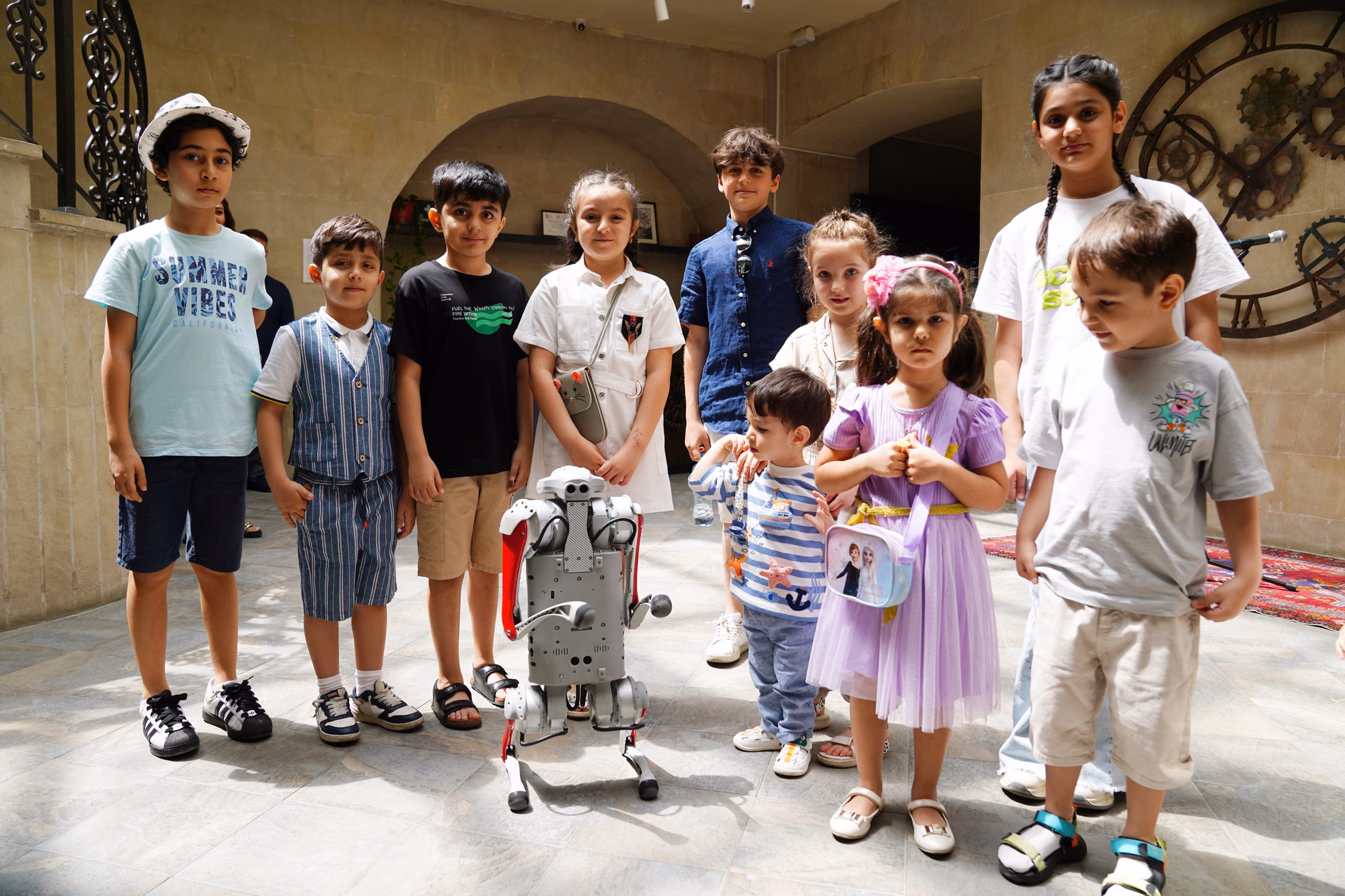 A diverse group of children joyfully interacting with a humanoid robot indoors, showcasing future technology.