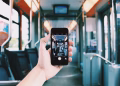 A hand holds a smartphone, capturing the interior of a train, creating a unique visual perspective.
