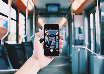 A hand holds a smartphone, capturing the interior of a train, creating a unique visual perspective.