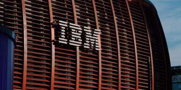 Close-up of IBM logo on a modern architectural facade under clear blue sky.