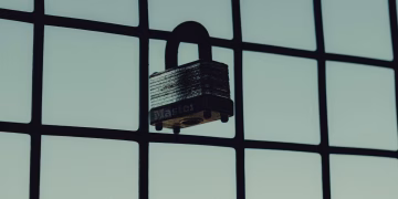 Close-up of a steel padlock on a mesh fence, symbolizing protection and security.