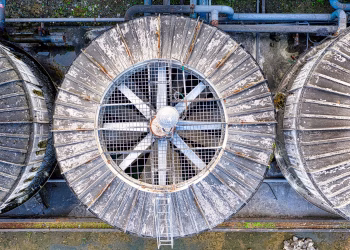 Drone top view of big shabby old metal ventilation fans on factory among pipes