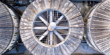 Drone top view of big shabby old metal ventilation fans on factory among pipes