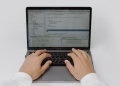 Close-up of hands coding on a laptop, showcasing software development in action.