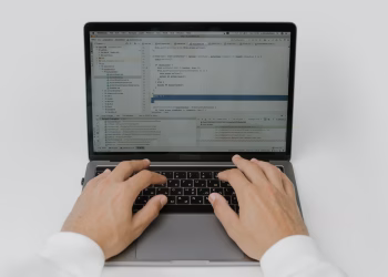 Close-up of hands coding on a laptop, showcasing software development in action.