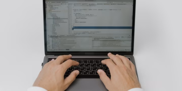 Close-up of hands coding on a laptop, showcasing software development in action.