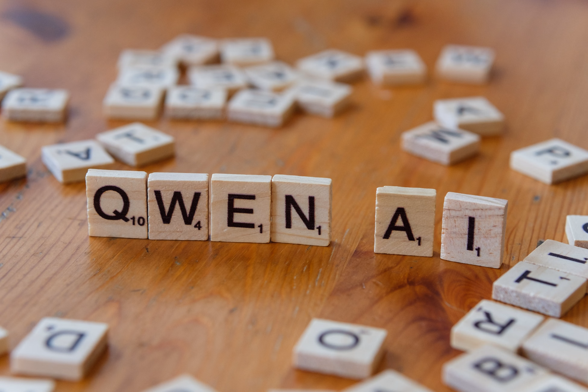 Scrabble-like tiles arranged to spell 'Qwen AI' on a wooden surface, depicting technology concepts.