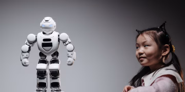 Young Asian girl interacts with a high-tech toy robot, showcasing innovation and curiosity.