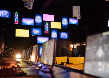 Illuminated gaming room with colorful screens and neon signs, creating an immersive gaming experience.