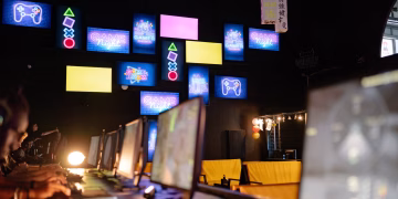 Illuminated gaming room with colorful screens and neon signs, creating an immersive gaming experience.