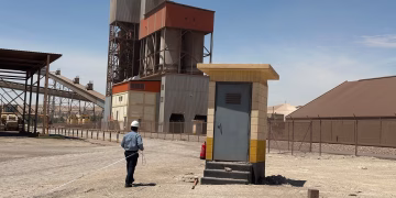 A cement manufacturing facility in Saudi Arabia with a worker on site under clear blue skies.