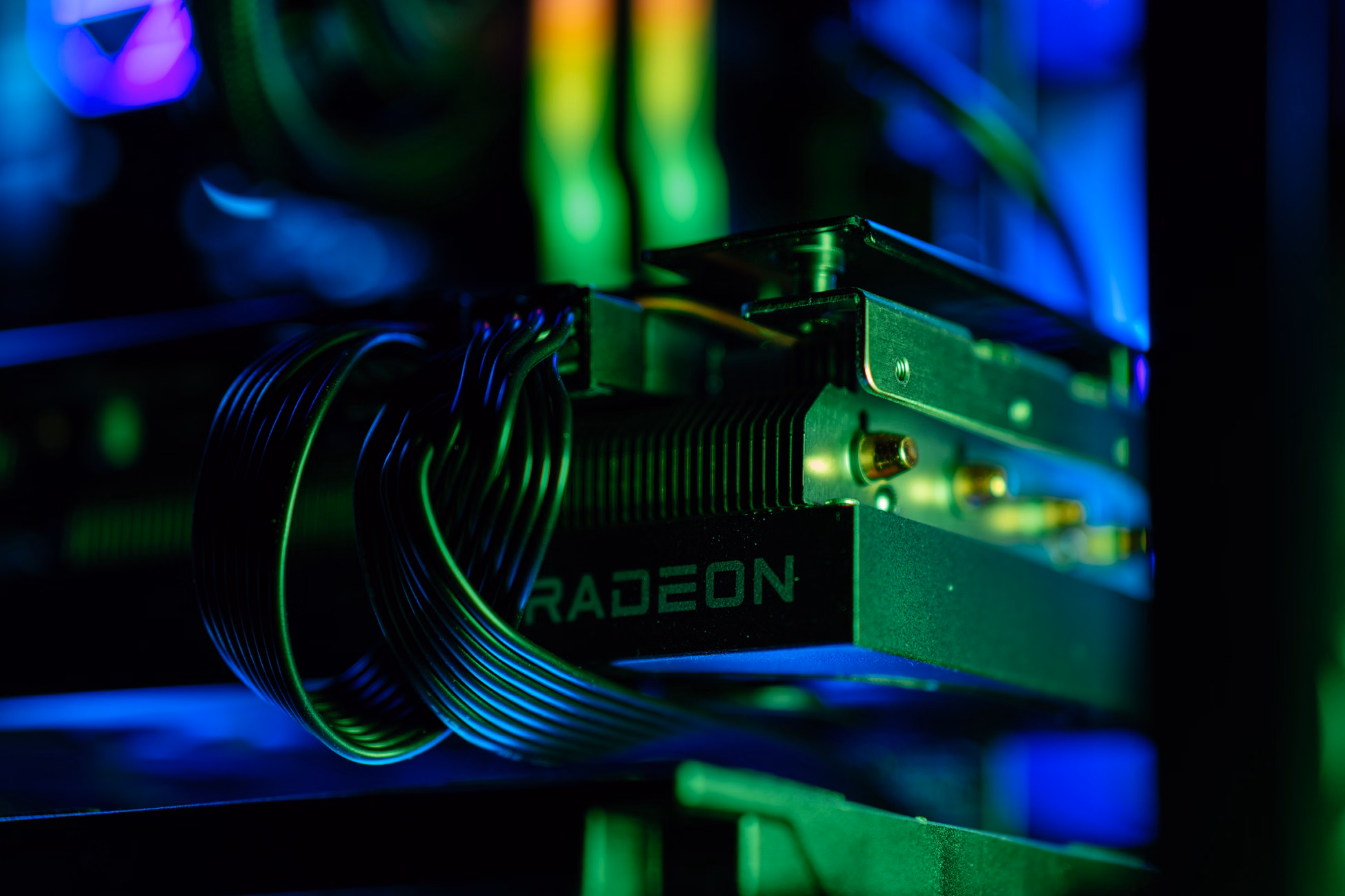 Detailed close-up of a gaming PC's Radeon graphics card with vibrant RGB lighting, showcasing cables and hardware.