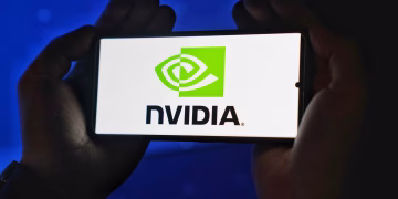 Hands holding a smartphone showing the NVIDIA logo on a bright screen.