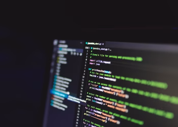 Programming code on a computer screen in a dark room, showcasing technology and IT expertise.