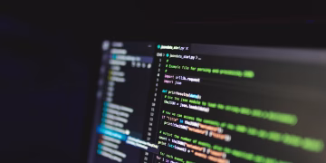 Programming code on a computer screen in a dark room, showcasing technology and IT expertise.