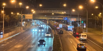 Traffic flows along a major Beijing highway, illuminated by bright streetlights at night.