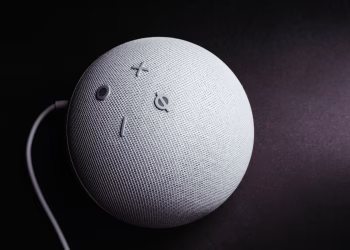 Close-up of a smart speaker on a black background, showcasing minimalistic elegance.