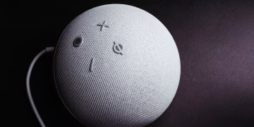 Close-up of a smart speaker on a black background, showcasing minimalistic elegance.