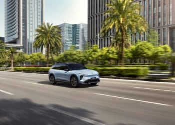 Image of a car speeding on a road in the sunshine.