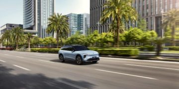 Image of a car speeding on a road in the sunshine.
