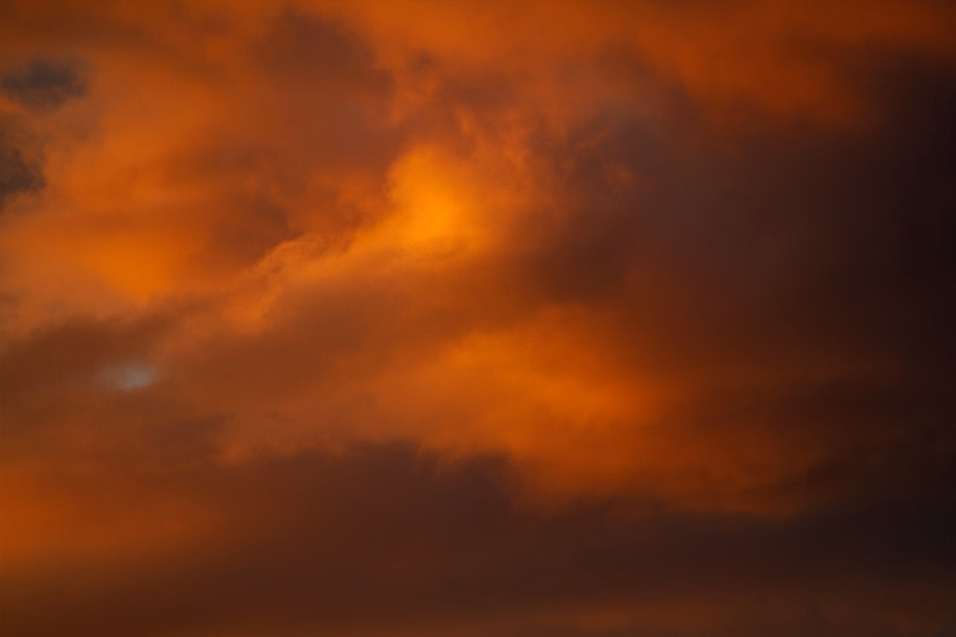 A vibrant and dramatic fiery orange sky with clouds during sunset.