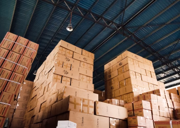 High stacks of cardboard boxes organized in a warehouse with a blue metal ceiling.