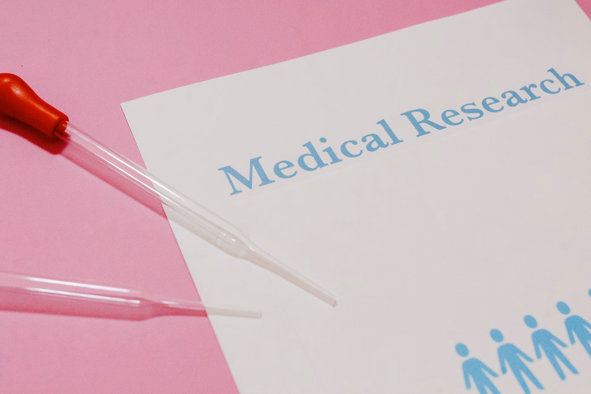Close-up of a medical research document and pipette on a pink surface, highlighting scientific research and healthcare.