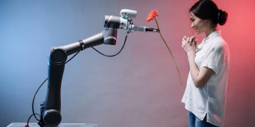 A robotic arm offers a flower to a woman in a display of technology and human connection.