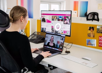 Woman engaged in a video call at her office desk, using technology for remote work and communication.