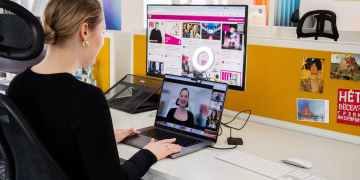 Woman engaged in a video call at her office desk, using technology for remote work and communication.