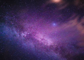 Purple-hued Milky Way galaxy with stars and nebula in a vast night sky.
