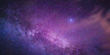 Purple-hued Milky Way galaxy with stars and nebula in a vast night sky.