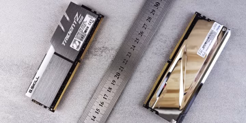 Close-up of computer memory modules and metal ruler placed on a textured gray surface.