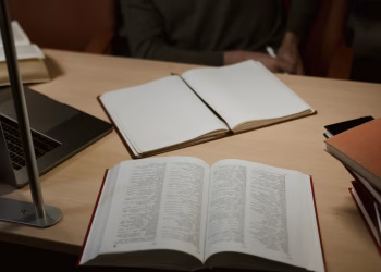 A warm, indoor study setup featuring open books and a laptop on a wooden desk, ideal for research and learning.