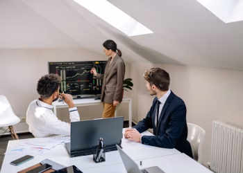 Professionals discussing stock market trends with charts in an office setting.