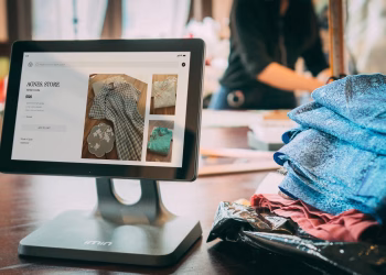 A digital point-of-sale system in a small fashion boutique with clothes displayed on a tablet.