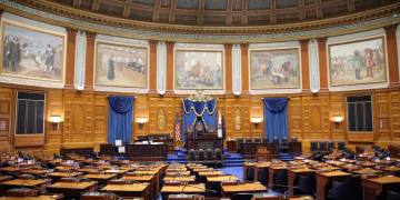 A beautiful view of the Massachusetts State House chamber with elegant decor and empty seating.