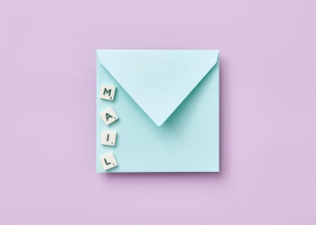 Minimalist flat lay showing a blue envelope and 'MAIL' spelled with Scrabble tiles on a purple background.