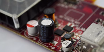 Detailed macro shot of a circuit board highlighting capacitors, chips, and circuits.