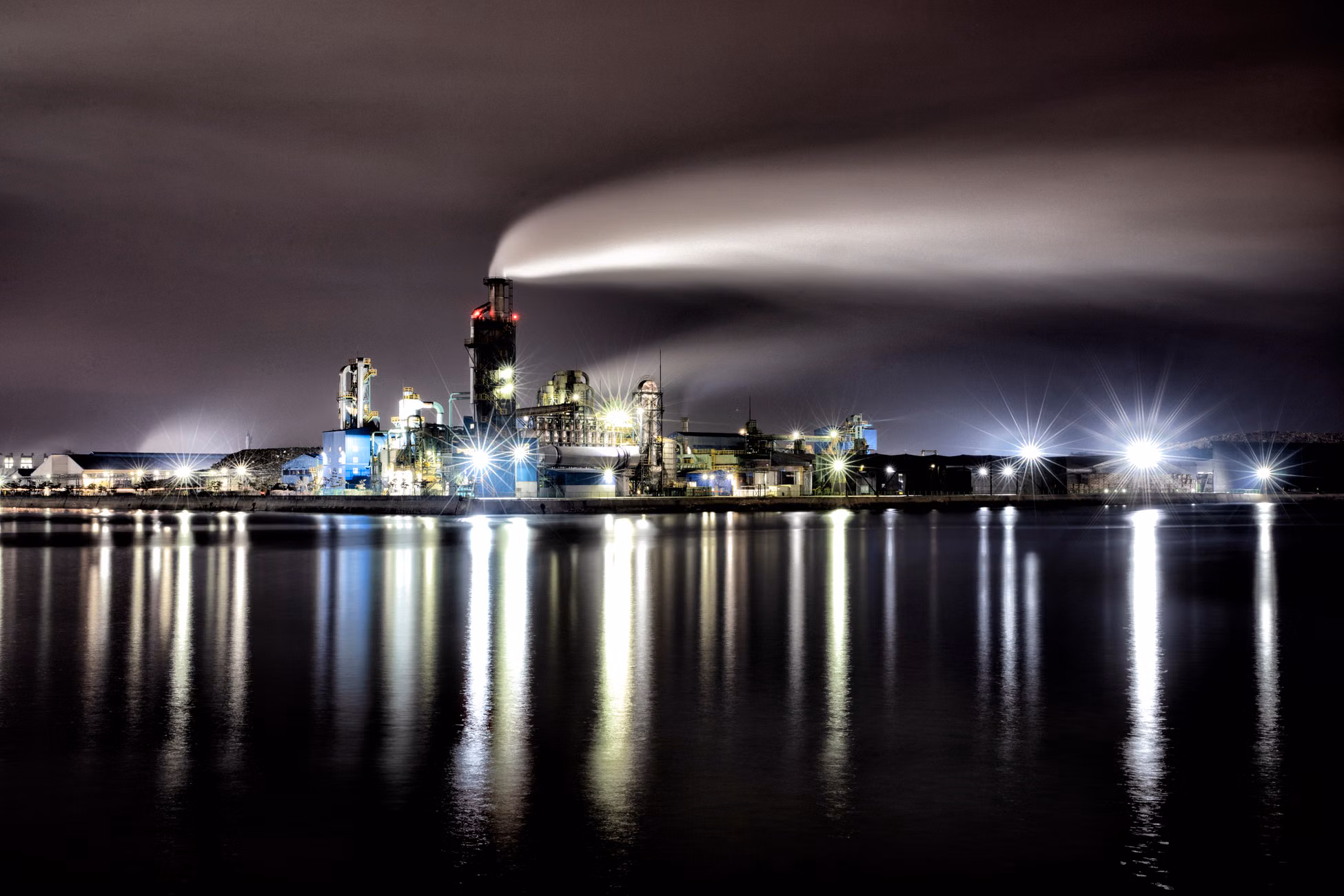 A night view of an illuminated industrial complex in Incheon, South Korea, reflecting vividly on tranquil waters.