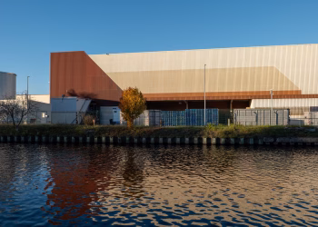 Modern industrial warehouse building reflected in calm river water.