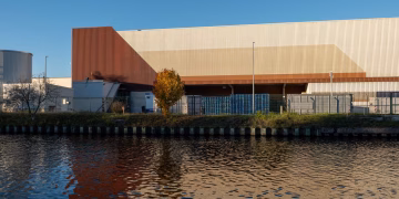Modern industrial warehouse building reflected in calm river water.