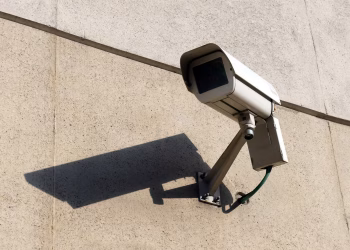 Modern surveillance camera mounted on a concrete wall casting a shadow.