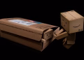 Whimsical cardboard robot figure emerging from a shipping box on a black background.
