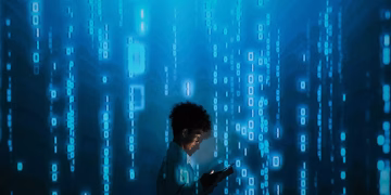 Silhouette of a person using a smartphone surrounded by digital binary code projections.